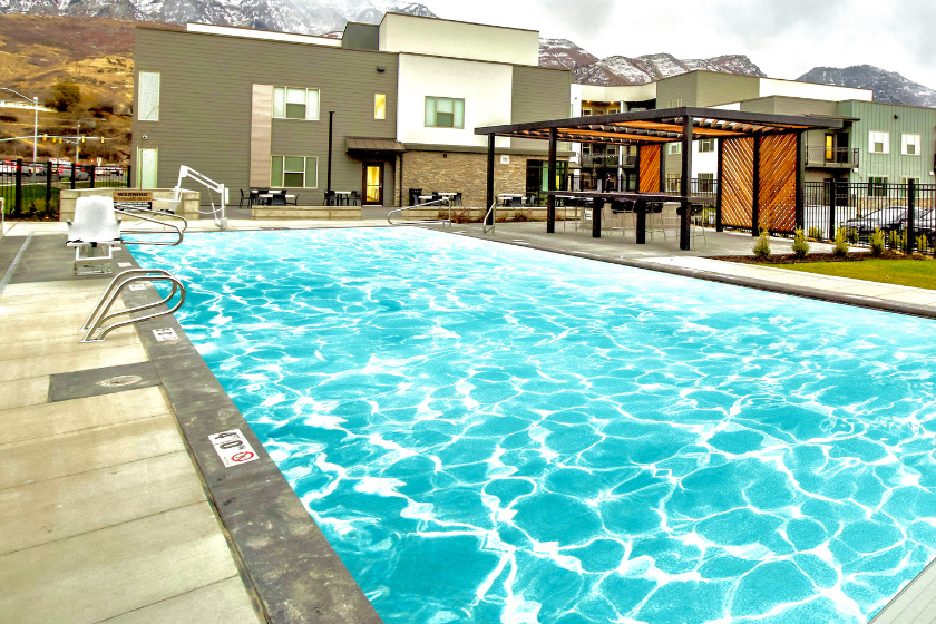 The pool and outdoor cabanas with tables and seating areas at The Flats at Riverwoods in Provo.